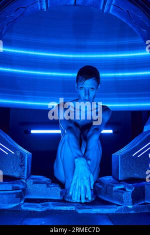 Innovations-Hub, außerirdischer humanoider Alien, der im experimentellen Hub im Neonlicht sitzt Stockfoto