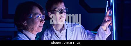 Junge internistische experimentelle Geräte im neonbeleuchteten Forschungszentrum der Zukunft Stockfoto