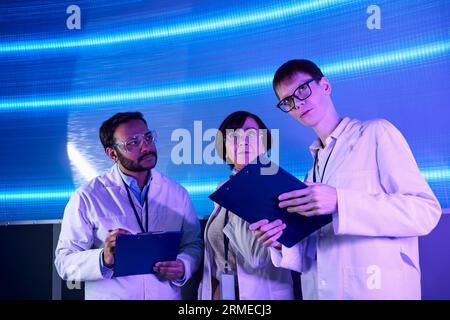 Zukunftsorientierte, junge Praktikanten, die sich in der Nähe multiethnischer Wissenschaftler im Innovationszentrum befinden Stockfoto