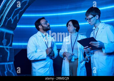 Zukunftsorientierte multiethnische Wissenschaftler, die in der Nähe junger Praktikanten im Innovationszentrum sprechen Stockfoto