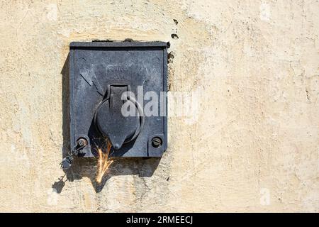 Altes schwarzes Elektrogerät mit Vintage-Wandstruktur, Funkenpfeil, Kurzschlusskonzept Stockfoto