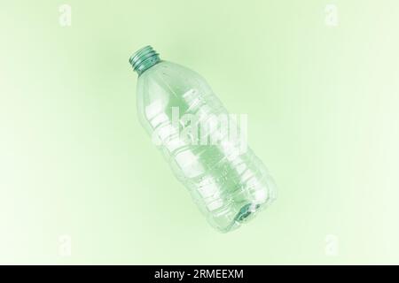 Eine minimalistische leere Plastikflasche vor einem pastellfarbenen hellgrünen Hintergrund Stockfoto