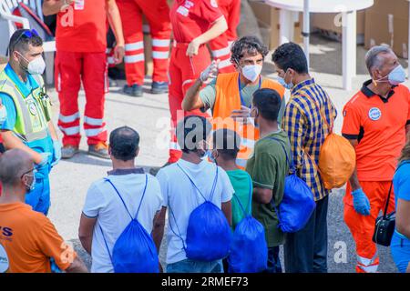 Livorno, Italien. 27. August 2023. Ein Rote-Kreuz-Operator erteilt einigen Migranten Anweisungen, die das Schiff Humanity 1 verlassen haben, bevor sie das Ausschiffungsgebiet verlassen. Das Schiff Humanity 1 der deutschen NGOs United 4 Rescue und SOS Humanity musste mehr als 1.000 Kilometer zurücklegen, um den vom italienischen Innenministerium zugewiesenen sicheren Hafen zu erreichen. Seit dem Inkrafttreten des "NRO-Dekrets" sind die Ausschiffungshäfen von NRO-Schiffen zunehmend von den Rettungszonen entfernt. (Bild: © Marcello Valeri/ZUMA Press Wire) NUR REDAKTIONELLE VERWENDUNG! Nicht Stockfoto