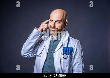 Foto eines Arztes mit Bart und Stethoskop mit blauem Hintergrund und medizinischem weißen Fell Stockfoto