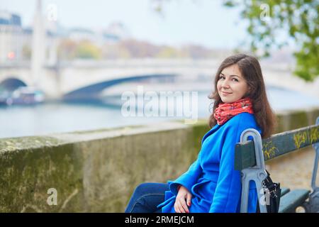 Wunderschöner junger Tourist in Paris, sitzt auf der Bank in der Nähe der seine Stockfoto