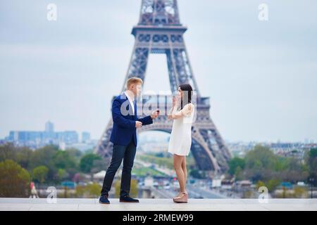 Romantische Verlobung in Paris, ein Mann, der seiner schönen Freundin nahe dem Eiffelturm einen Vorschlag machte. Überraschendes Angebot oder Konzept für eine Lösung Stockfoto