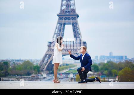 Romantische Verlobung in Paris, ein Mann, der seiner schönen Freundin nahe dem Eiffelturm einen Vorschlag machte. Überraschendes Angebot oder Konzept für eine Lösung Stockfoto