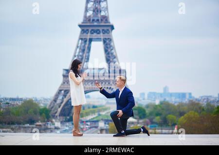Romantische Verlobung in Paris, ein Mann, der seiner schönen Freundin nahe dem Eiffelturm einen Vorschlag machte. Überraschendes Angebot oder Konzept für eine Lösung Stockfoto