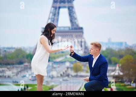 Romantische Verlobung in Paris, ein Mann, der seiner schönen Freundin nahe dem Eiffelturm einen Vorschlag machte. Überraschendes Angebot oder Konzept für eine Lösung Stockfoto