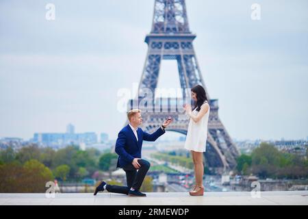 Romantische Verlobung in Paris, ein Mann, der seiner schönen Freundin nahe dem Eiffelturm einen Vorschlag machte. Überraschendes Angebot oder Konzept für eine Lösung Stockfoto