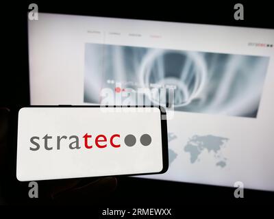 Person mit Smartphone mit Logo des deutschen Diagnoseunternehmens STRATEC SE auf dem Bildschirm vor der Website. Konzentrieren Sie sich auf das Display des Telefons. Stockfoto