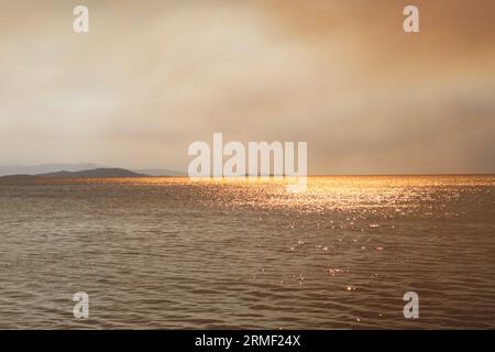 Rauch und Feuer auf den griechischen Inseln im Sommer vom Meer Stockfoto