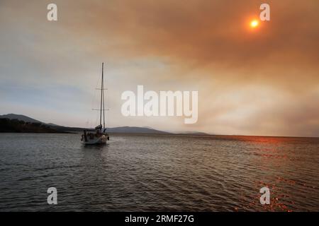 Rauch und Feuer auf den griechischen Inseln im Sommer vom Meer Stockfoto