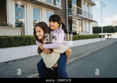 Schwestern, die Spaß haben und sich gegenseitig Huckepack fahren lassen Stockfoto