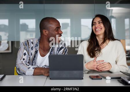 Lächelnde Kollegen, die bei Geschäftstreffen sitzen und reden Stockfoto