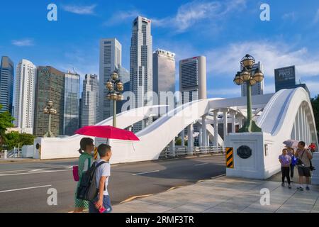 Fußgänger, die über die Elgin Bridge über den Singapore River laufen, Singapur, die Hochhäuser des Geschäftsviertels im Hintergrund Stockfoto