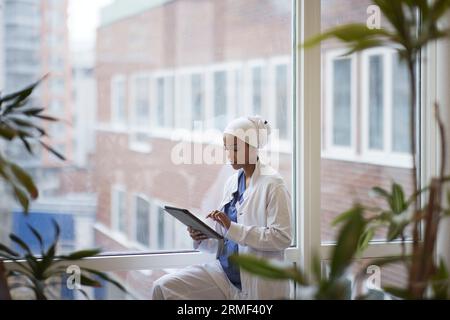 Arztin stehend und mit digitaler Tablette Stockfoto