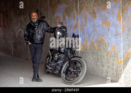 Reifer Biker in Lederkleidung, der neben dem Motorrad steht Stockfoto