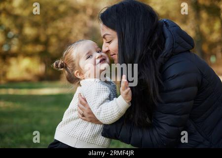 Glückliche Mutter umarmt Tochter im Park Stockfoto