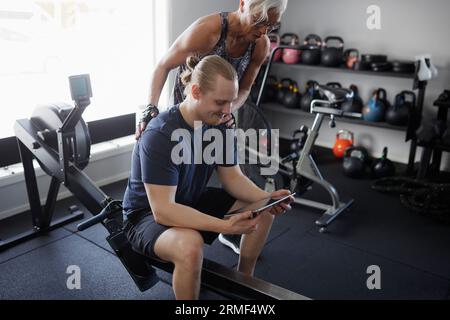 Mann und Frau, die sich im Fitnessstudio ein digitales Tablet ansehen Stockfoto