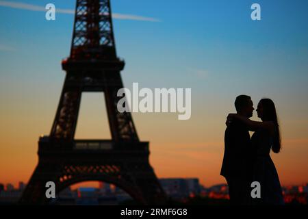 Silhouetten eines wunderschönen verliebten Paares bei Sonnenaufgang oder Sonnenuntergang vor dem Eiffelturm, Paris, Frankreich Stockfoto