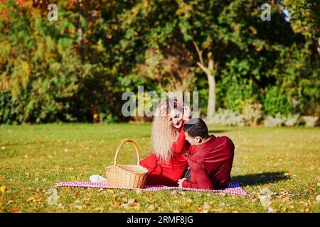 Ein romantisches Paar, das am Herbsttag ein Picknick auf dem Gras genießt Stockfoto