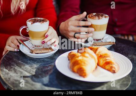 Romantisches Paar im Pariser Café. Touristen trinken Kaffee und essen Croissants im Restaurant in Paris, Frankreich Stockfoto