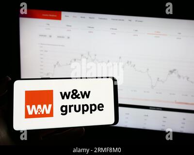 Person mit Mobiltelefon mit Logo der Wüstenrot Württembergischen AG (WW) auf dem Bildschirm vor der Webseite. Konzentrieren Sie sich auf das Display des Telefons. Stockfoto