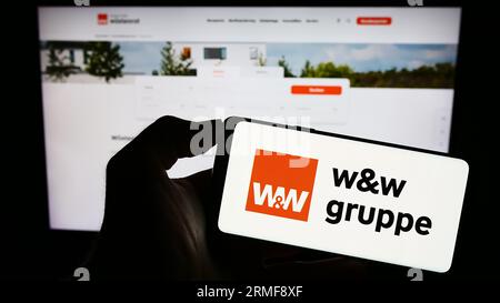 Person mit Smartphone mit Logo der Wüstenrot Württembergischen AG (WW) auf dem Bildschirm vor der Website. Konzentrieren Sie sich auf das Display des Telefons. Stockfoto