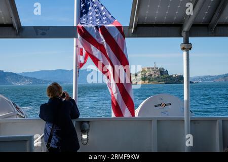 Ein Tourist, der ein Foto von Alcatraz von der Fähre in San Francisco, Kalifornien, USA macht Stockfoto