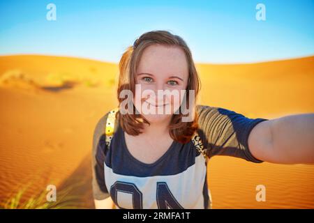 Glücklicher lächelnder Tourist, der Selfie mit Sanddünen in der Sahara nimmt, in Erg Chebby, Merzouga, Marokko Stockfoto