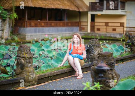 Europäischer Tourist sitzt in der Nähe des Lotus-Teiches Lotus-Teich im Pura Saraswati-Tempel in Ubud, Bali Stockfoto