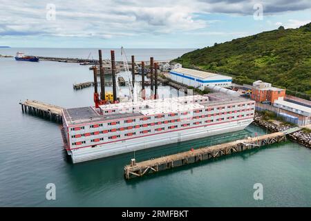 Portland, Dorset, Großbritannien. 28. August 2023. Allgemeine Sicht aus der Luft des leeren Bibby Stockholm Asylbewerberschiffs am Portland Port bei Weymouth in Dorset, der wegen der tödlichen Legionellenbakterien im Wasser evakuiert wurde. Es wird berichtet, dass die Migranten nicht vor Anfang September wieder in den Binnenschiffer einsteigen werden, da sie daran arbeiten, die Legionellenbakterien zu entfernen und zu testen, um festzustellen, ob sie ausgerottet sind. Die Feuerwehrgewerkschaft droht auch rechtliche Schritte, weil sie befürchtet, dass das Schiff unsicher ist. Bildnachweis: Graham Hunt/Alamy Live News Stockfoto