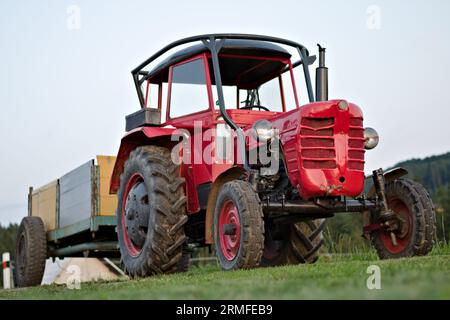 Vintage rot tschechischer Traktor Zetor mit Anhänger auf einem kleinen Dorfhof. Stockfoto