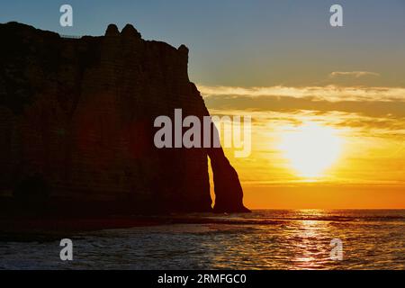 Malerischer Blick auf Etretat mit seinem Strand und berühmten Klippen mit Bögen bei Sonnenuntergang. Konzentrieren Sie sich auf Klippen Stockfoto