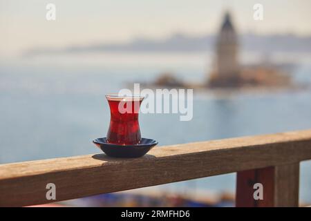 Türkisches Glas in Form einer Tulpe gefüllt mit heißem schwarzem Tee mit Blick auf den Maiden's Tower im Uskudar-Viertel auf der asiatischen Seite von Istanbul, Türkei Stockfoto