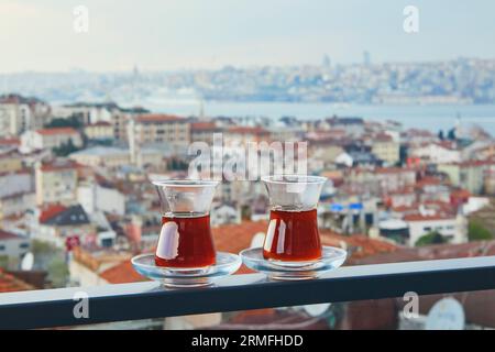 Zwei türkische Gläser in Form einer Tulpe gefüllt mit heißem schwarzem Tee mit Blick auf die Dächer des Uskudar-Viertels auf der asiatischen Seite von Istanbul, Türkei Stockfoto