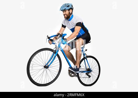 Bärtiger kaukasischer Radfahrer, der Sportausrüstung trägt, Fahrrad fährt. Seitenansicht des männlichen Radfahrers, der sich bemüht, schnell zu fahren, isoliert auf weißem Studiohintergrund Stockfoto