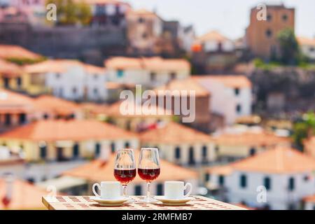 Zwei Gläser Madeira-Wein und zwei Tassen frischer Espresso-Kaffee im Straßencafé mit Blick auf Funchal, Madeira, Portugal Stockfoto