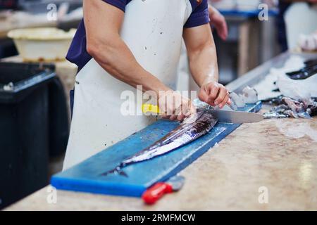 Man schneidet auf dem traditionellen Fischmarkt in Funchal, Madeira, Portugal, Atlantische Largehead-Haarschwänze (auf Portugiesisch auch espada genannt) Stockfoto