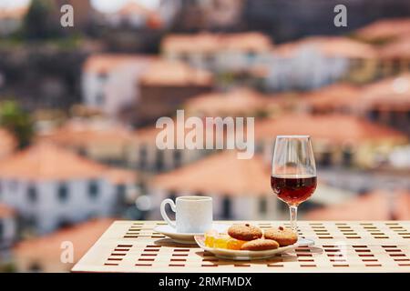 Zwei Gläser Madeira-Wein und zwei Tassen frischer Espresso-Kaffee im Straßencafé mit Blick auf Funchal, Madeira, Portugal Stockfoto