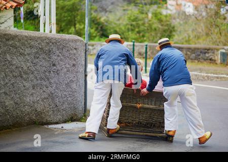 Berühmte Rodelfahrer, die den traditionellen Rohrrohrschlitten bergab auf den Straßen von Funchal, Madeira, Portugal, fahren Stockfoto