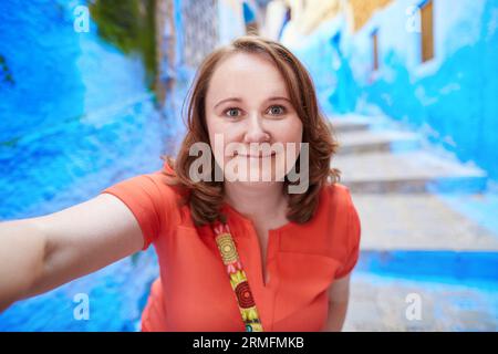 Glücklicher junger Tourist nimmt Selfie auf einer Straße in Medina von Chefchaouen, Marokko Stockfoto