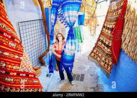 Europäischer Tourist auf einem Markt für Straßenteppiche in Chefchaouen, Marokko, einer kleinen Stadt im Nordwesten Marokkos, die für ihre blauen Gebäude bekannt ist Stockfoto