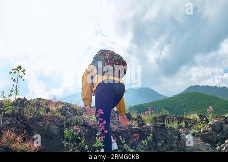 Wandern auf dem höchsten Vulkan Kontinentaleuropas - Ätna. Unerkennbare Wanderfrau, die auf dem schwarzen Sand des Lavasteins des Ätna klettert, und genießt f Stockfoto