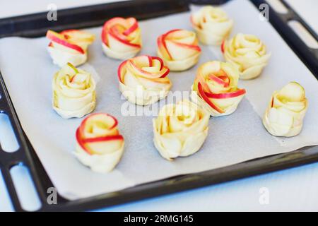 Apfelkuchen in Form von Rosen auf einer Backform, bevor sie in den Ofen gehen. Selektiver Fokus Stockfoto