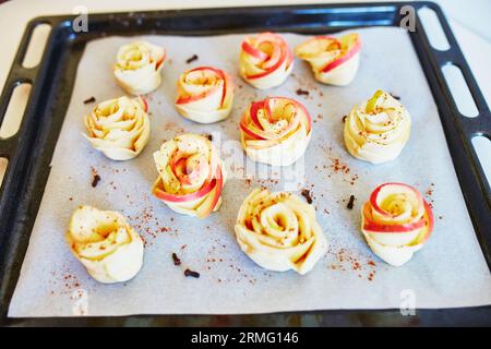 Apfelkuchen in Form von Rosen mit Zimt und Nelken auf einer Backform, bevor sie in den Ofen gehen. Selektiver Fokus Stockfoto