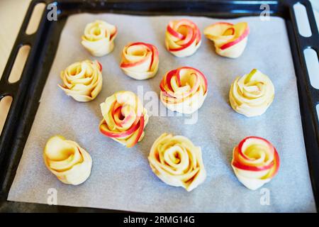 Apfelkuchen in Form von Rosen auf einer Backform, bevor sie in den Ofen gehen. Selektiver Fokus Stockfoto