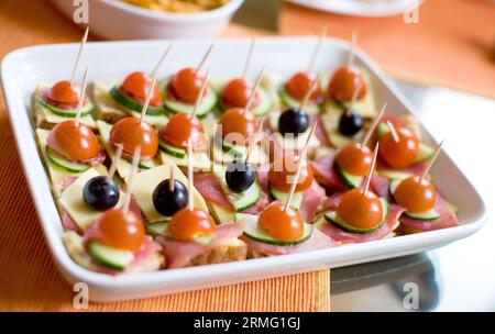 Kleine Canapes mit Schinken, Käse, Gurken, Kirschtomaten und schwarzen Oliven Stockfoto