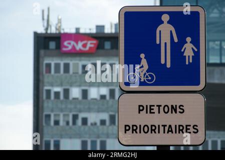 Ein Straßenschild mit dem französischen Text „Pietons Prioritaires“. (Bevorzugte Fußgänger, in englischer Sprache). Das Schild befindet sich vor einem Gebäude der SNCF, Th Stockfoto